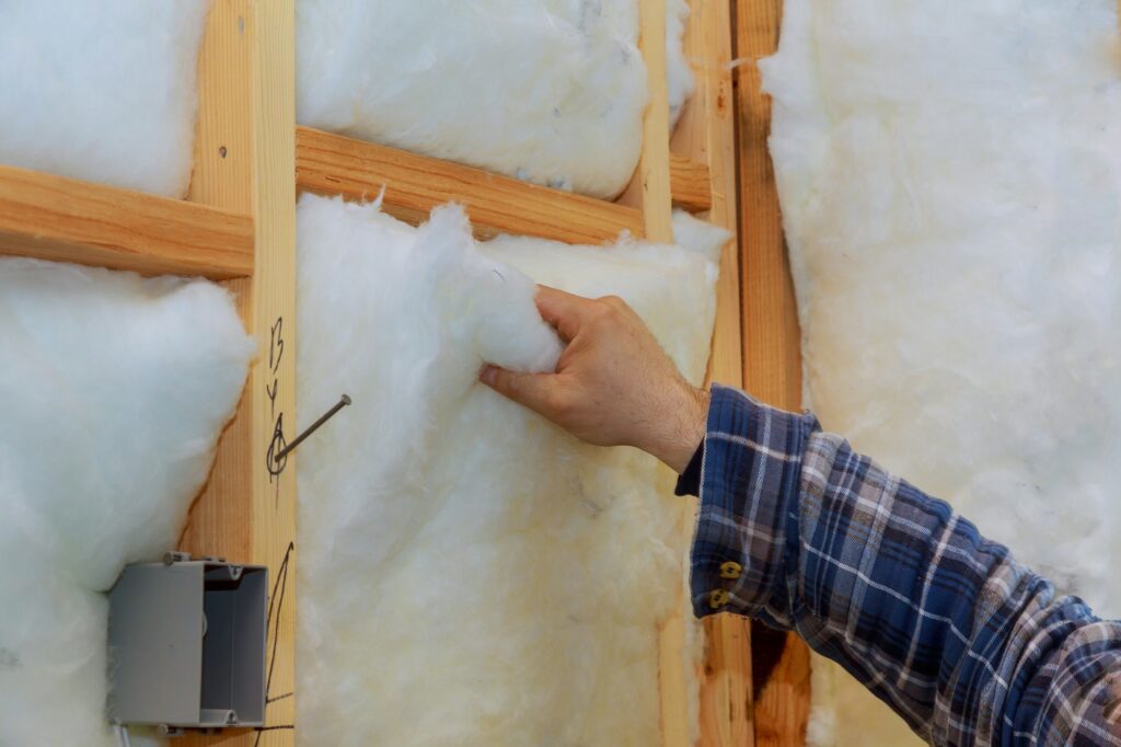 Worker in insulating rock wool insulation in wooden frame for future house walls for comfortable