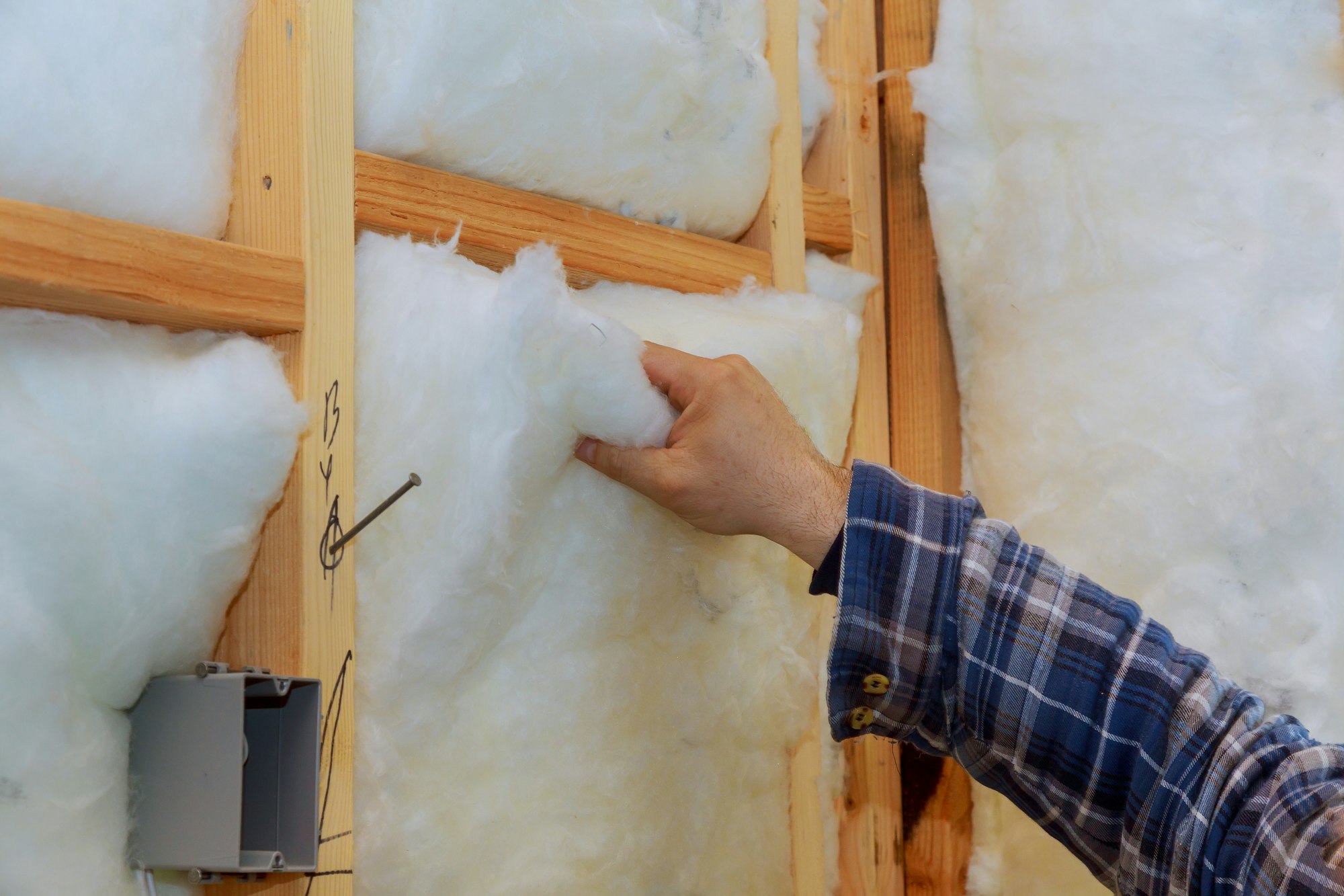Worker in insulating rock wool insulation in wooden frame for future house walls for comfortable